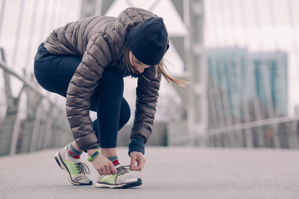 woman in athletic clothes tying her shoe laces on the street