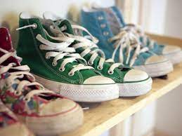 ένα ράφι με παλιά φορεμένα converse all star sneakers που έχουν λευκά κορδόνια