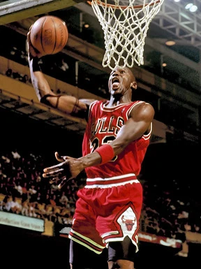 Ο Jordan φορά την κόκκινη φανέλα των Chicago Bulls και είναι στον αέρα για ένα κάρφωμα