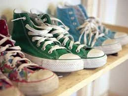 ένα ράφι με παλιά φορεμένα converse all star sneakers που έχουν λευκά κορδόνια