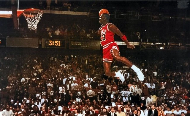 Michael Jordan flying to dunk in the basketball stadium